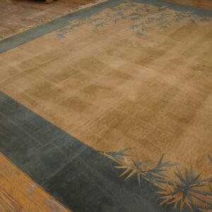 Tan area rug featuring a thick teal border and stylized blue foliage rests on a rustic wood floor.