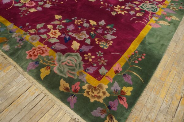 A plush magenta rug with a green and yellow border features intricate multicolor floral designs on wood floors.