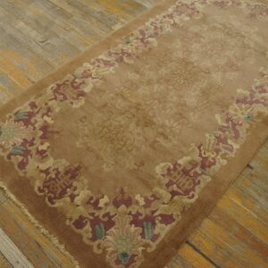 Brown area rug with subtle field pattern and colorful floral border on rustic wood plank flooring.