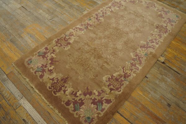Brown area rug with subtle field pattern and colorful floral border on rustic wood plank flooring.