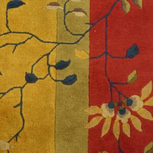 A textured pile rug detail featuring golden yellow, olive green, and red vertical color blocks with dark floral vines.