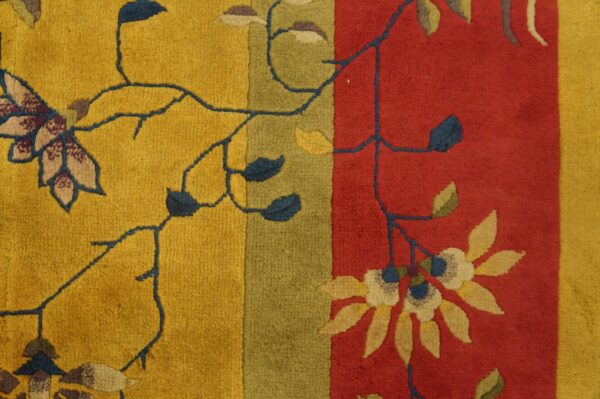 A textured pile rug detail featuring golden yellow, olive green, and red vertical color blocks with dark floral vines.