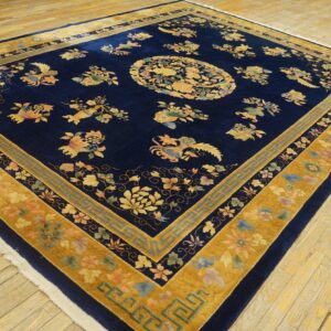 High-pile navy rug with multi-colored floral and gold borders displayed on worn wood planks.