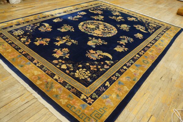 High-pile navy rug with multi-colored floral and gold borders displayed on worn wood planks.