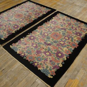 Two matching rugs with colorful floral patterns and black borders displayed on distressed light wooden flooring.