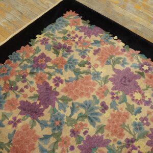 Floral rug corner featuring peach, purple, and blue flowers on a tan field with a solid black border.
