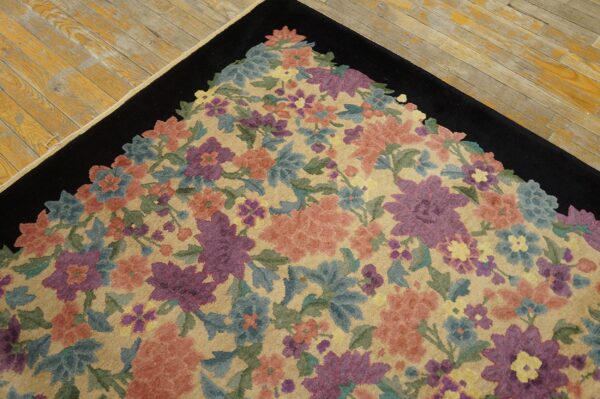 Floral rug corner featuring peach, purple, and blue flowers on a tan field with a solid black border.