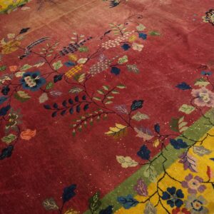 Low-pile red rug featuring colorful floral vines, birds, and a butterfly, bordered by bright yellow on wood floor.