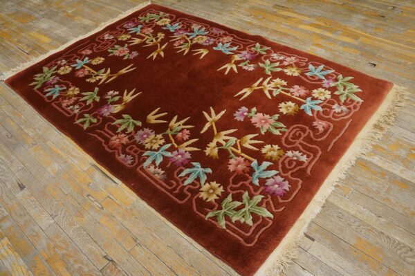 Rust rug with a colorful floral and bamboo wreath design rests on distressed wood planks.