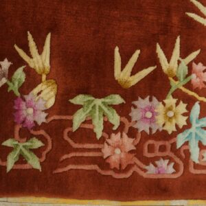 Plush red rug detail showing pink, yellow, and blue floral motifs with a raised, carved pile texture.