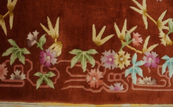 Plush red rug detail showing pink, yellow, and blue floral motifs with a raised, carved pile texture.