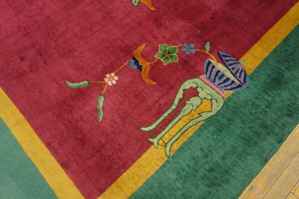 Magenta and green patterned rug corner with a yellow stripe rests on distressed wood flooring.