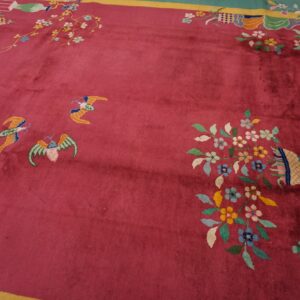 High-pile magenta rug featuring colorful floral designs, butterflies, and a teal and yellow border.