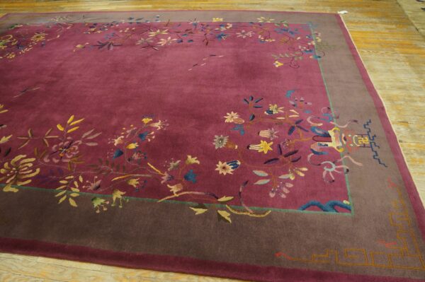A deep magenta rug featuring colorful vines and flowers is framed by a wide taupe border on wood floors.