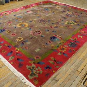 Multi-colored floral rug featuring a taupe field, green stripe, and wide red border on wood planks.