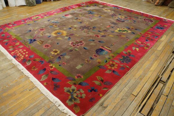 Multi-colored floral rug featuring a taupe field, green stripe, and wide red border on wood planks.