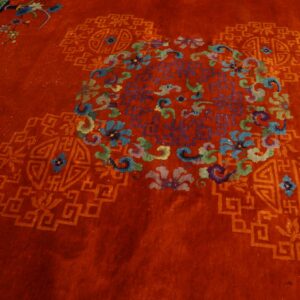 Deep red rug with high pile featuring a central multicolored floral medallion and geometric fretwork.