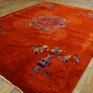 Large red-orange rug with central medallion and bright floral designs rests on rustic wooden planks.