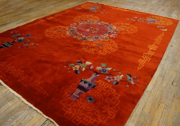 Large red-orange rug with central medallion and bright floral designs rests on rustic wooden planks.