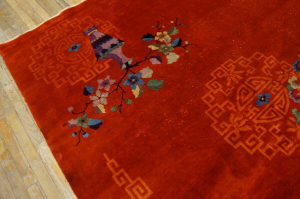 Multicolored floral and vase designs accent a high-pile red rug lying on light wood floors.
