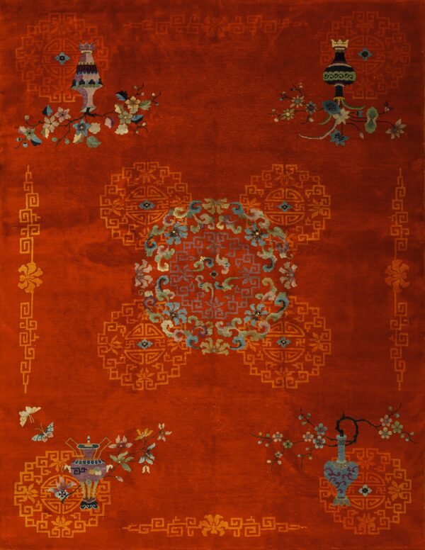 A rust-colored rug features ornate vases, pastel floral vines, a central medallion, and gold geometric borders.