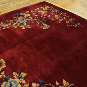 Deep crimson rug featuring sprawling yellow and blue floral designs on a light wood floor.