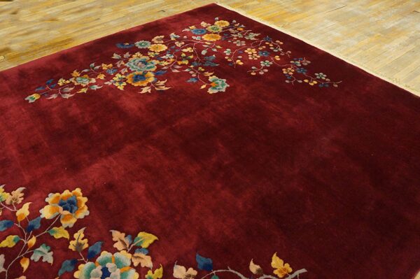 Deep crimson rug featuring sprawling yellow and blue floral designs on a light wood floor.