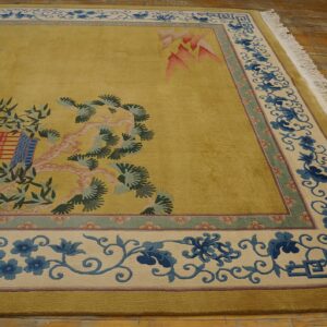 Chartreuse rug with a landscape pattern and intricate blue floral border rests on distressed wood planks.