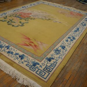 Yellow rug with stylized pink and green patterns, featuring blue floral borders on distressed wood flooring.
