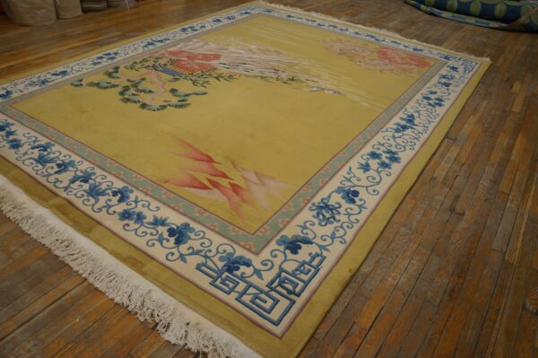 Yellow rug with stylized pink and green patterns, featuring blue floral borders on distressed wood flooring.