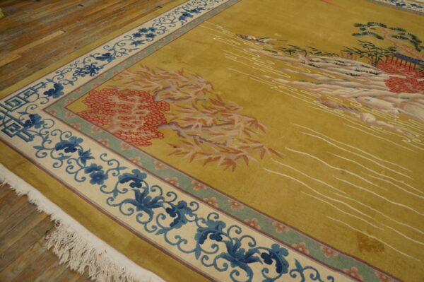 Chartreuse rug with blue scroll borders and pictorial scene laid on distressed plank hardwood flooring.