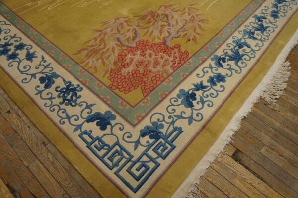 Mustard yellow rug featuring a border of blue floral vines and greek keys resting on rustic wood floors.