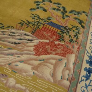 Pictorial rug showing a yellow landscape, terracotta accents, and a wide cream border with blue floral vines.