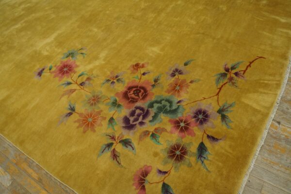 Golden yellow high-pile rug displays an arrangement of pink, purple, and green flowers on wood flooring.