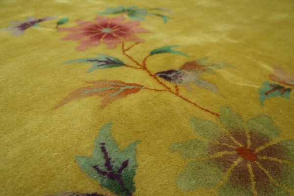 Gold rug detailed with large pink and green flowers and leaves on delicate rust-colored vines.