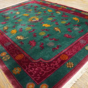 Teal rug with a detailed magenta border and scattered gold and red cloud and bird patterns on wood flooring.