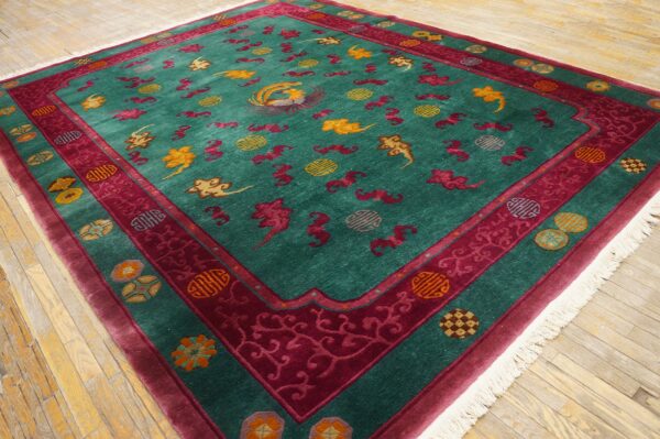 Teal rug with a detailed magenta border and scattered gold and red cloud and bird patterns on wood flooring.