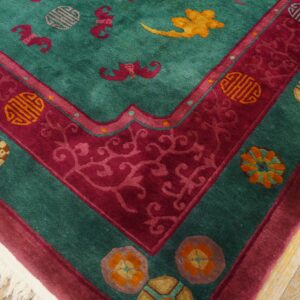 Plush teal rug with a patterned magenta border and symbolic motifs rests on light hardwood flooring.