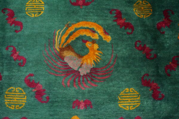 High-pile teal rug displaying a large colorful rooster surrounded by small red stylized bats and yellow symbols.