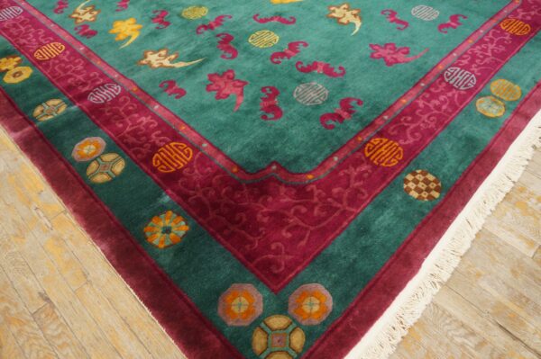 Teal rug with high pile features scattered pink and yellow motifs and ornate magenta borders on wood flooring.