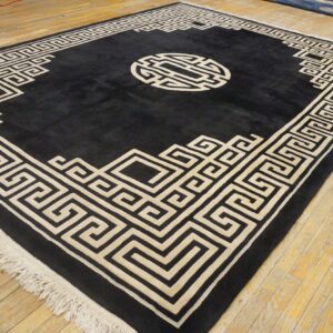 Black high-pile rug with a cream geometric border and medallion on distressed wood plank flooring.