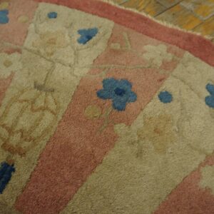 Close-up of a low-pile rug featuring dusty pink, beige, and blue floral panels on rustic wood flooring.