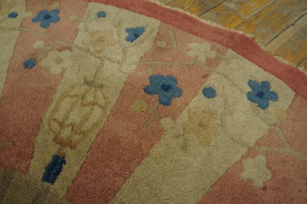Close-up of a low-pile rug featuring dusty pink, beige, and blue floral panels on rustic wood flooring.
