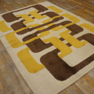 Shag rug in cream, brown, and yellow with a large abstract interlocking pattern on distressed wood flooring.