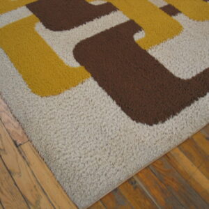 Brown, yellow, and beige high-pile rug with a geometric pattern on wood flooring.