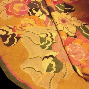 Folded round rug showcasing large multicolored floral patterns against a dominant golden yellow field.