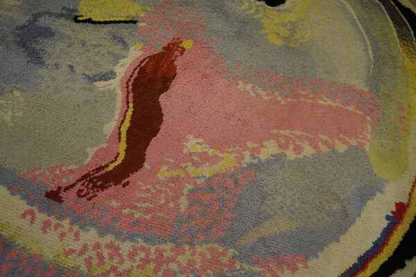 Abstract medium pile rug detail featuring large fields of pink, dusty blue, yellow, and deep red.