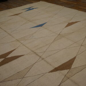 Textured beige rug featuring an abstract diamond pattern with fine lines and large brown and blue shapes.