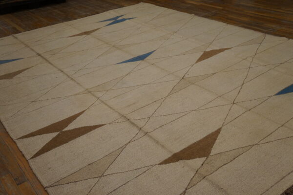 Textured beige rug featuring an abstract diamond pattern with fine lines and large brown and blue shapes.