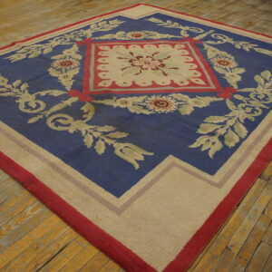 Blue rug featuring a large central beige and red floral design, lying on rustic wood plank flooring.